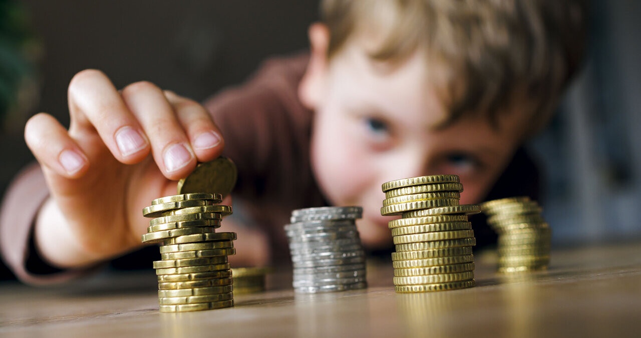 Ein kleiner Junge stapelt seine Münzen. Finanzbildung in der Schule? Schön wär's. Tatsächlich lernen Kinder den Umgang mit Geld häufig von den Eltern. Wie ihr eurem Kind beim Sparen und Anlegen helft, und welche Rolle Taschengeld dabei spielt. | Bild: picture alliance / photothek | Thomas Trutschel