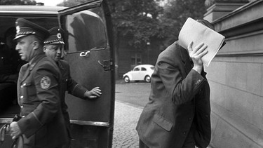 Der Hauptangeklagte im Doppelagentenprozess Heinz Felfe verdeckt auf dem Weg ins Gerichtsgebäude am 08.07.1963 mit einem Aktendeckel sein Gesicht. | Bild: picture alliance / Fritz Fischer | Fritz Fischer
