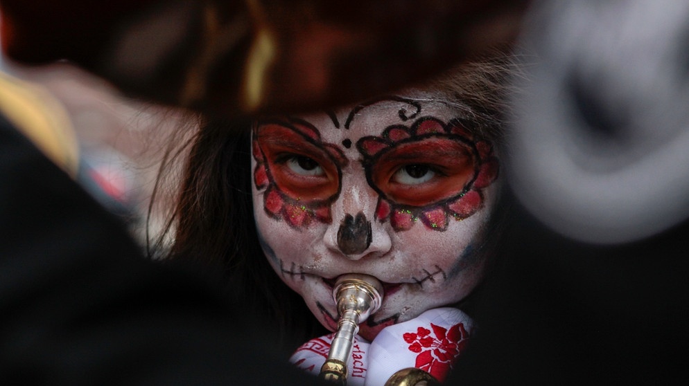 Geschminkter Musiker am Totentag in Mexiko. Am 1. November, dem Día de los Muertos, besuchen auch die Mariachis die prächtig geschmückten Gräber. Am 31. Oktober ist Halloween. Woher stammt der Brauch, wie ist er nach Deutschland gekommen und warum schnitzen und beleuchten wir Kürbisse? | Bild: picture-alliance/dpa