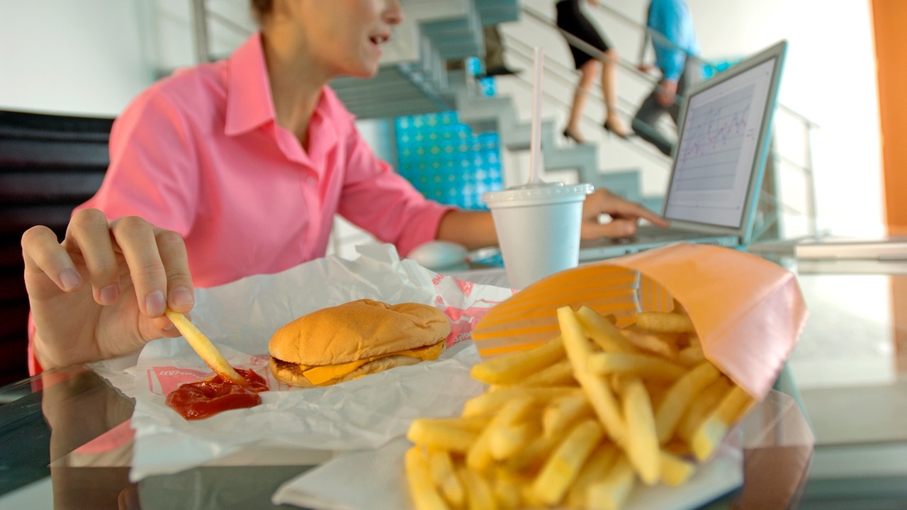 Junge Frau arbeitet am Laptop und isst nebenbei Pommes Frites. Esst ihr oft unter Stress? Der kann euer Essverhalten beeinflussen: Heisshunger oder Appetitlosigkeit sind die Folgen. Tipps für eine gesunde Ernährung. | Bild: picture alliance / photononstop | A. Chederros