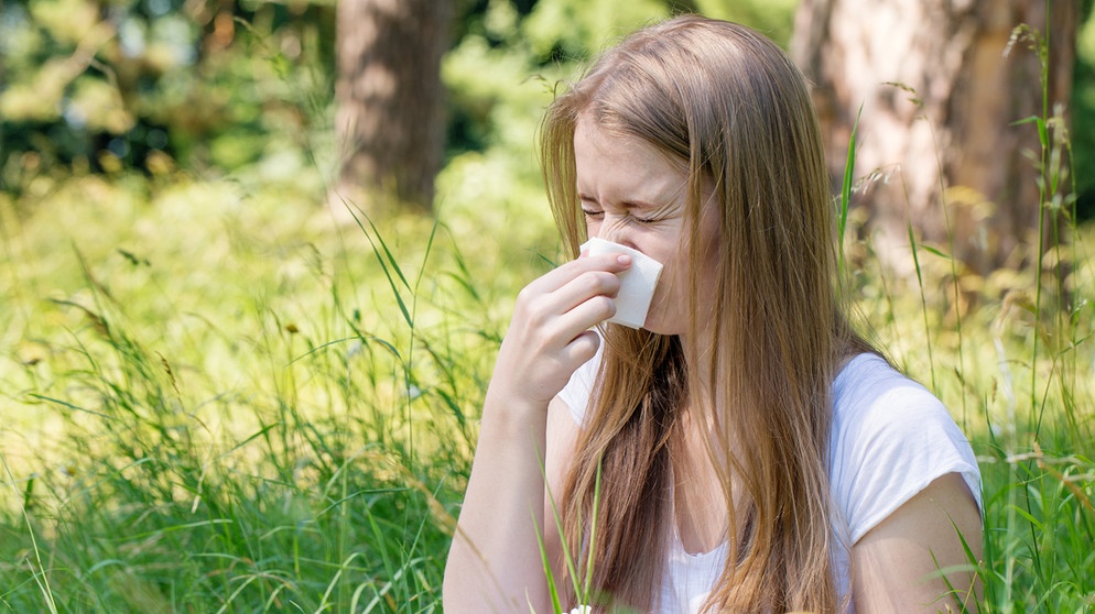 Symbolbild Heuschnupden / Pollenallergie: Junge Frau mit langen blonden Haaren sitzt auf einer Wiese und schnäuzt in ein Taschentuch. | Bild: colourbox.com