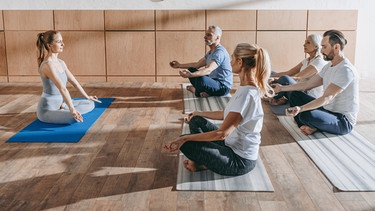 Menschen machen auf Matten Yoga. Yoga wirkt nachweislich besser als andere Sportarten gegen chronische Schmerzen und Stress und tut Körper und Seele gut. Warum euch Yoga gesund und fit hält.  | Bild: colourbox.com