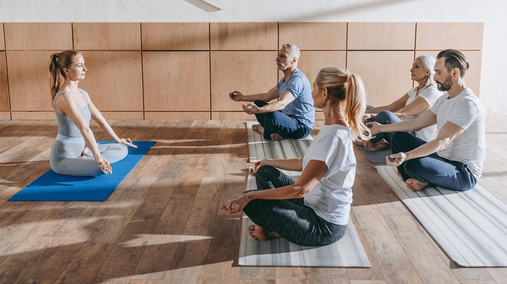 Menschen machen auf Matten Yoga. Yoga wirkt nachweislich besser als andere Sportarten gegen chronische Schmerzen und Stress und tut Körper und Seele gut. Warum euch Yoga gesund und fit hält.  | Bild: colourbox.com