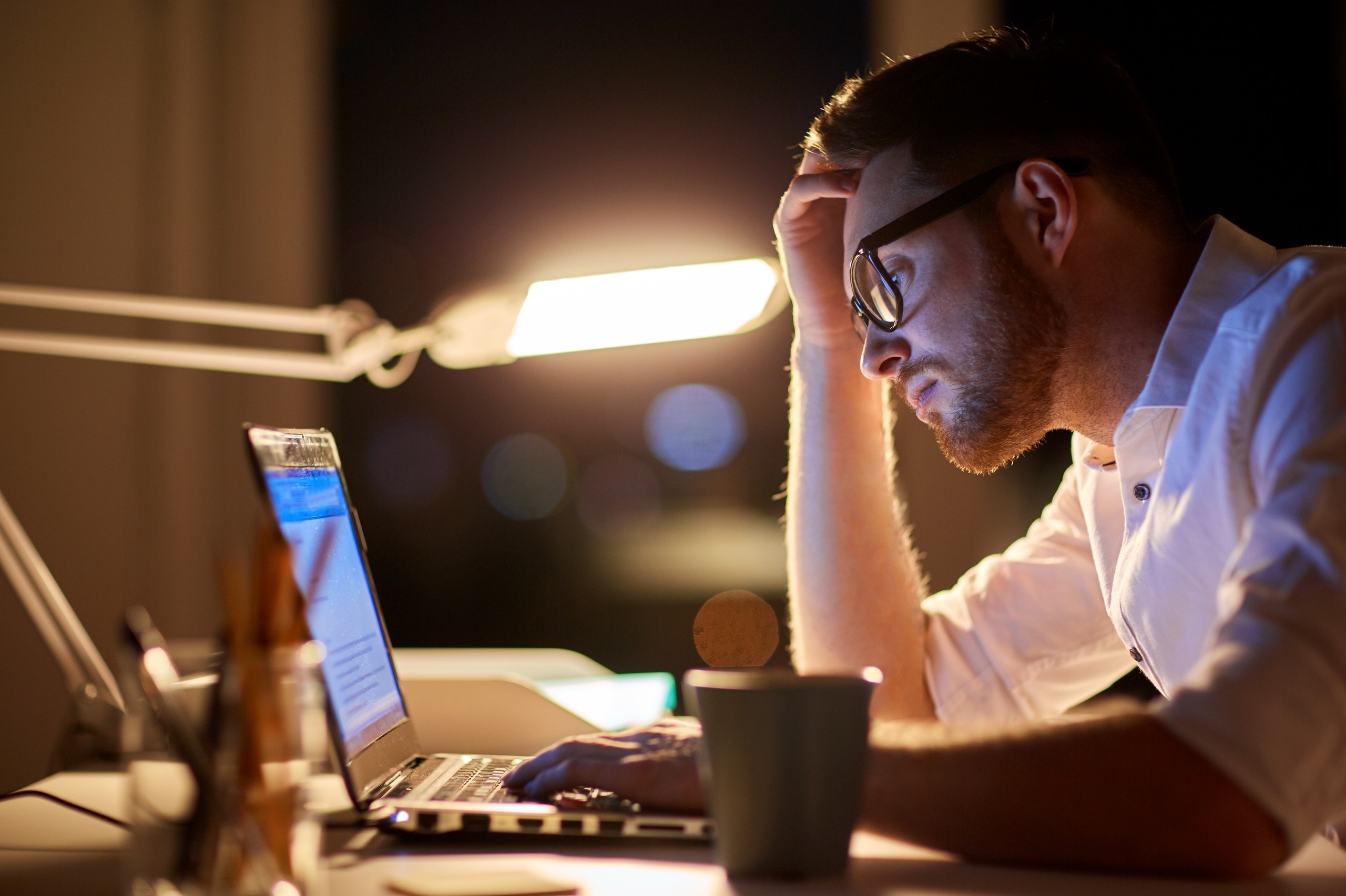 Ein Mann arbeitet bis spät in die Nacht an seinem Laptop, sieht unglücklich aus. Ob beim Sport, in der Beziehung oder im Beruf, Durchhaltevermögen ist überall gefragt. Doch ab wann wird durchhalten schädlich? Darauf könnt ihr achten. | Bild: colourbox.com/ Syda Productions