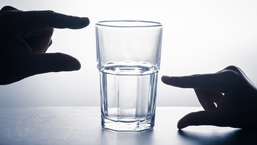 Zwei Hände messen, wie voll ein Glas ist. Denkt ihr oft negativ? Wir erklären, warum manche Menschen eher Pessimisten oder Optimisten sind, was 'pessimistisch' bedeutet - und ob das wirklich immer schlecht ist. | Bild: colourbox.com