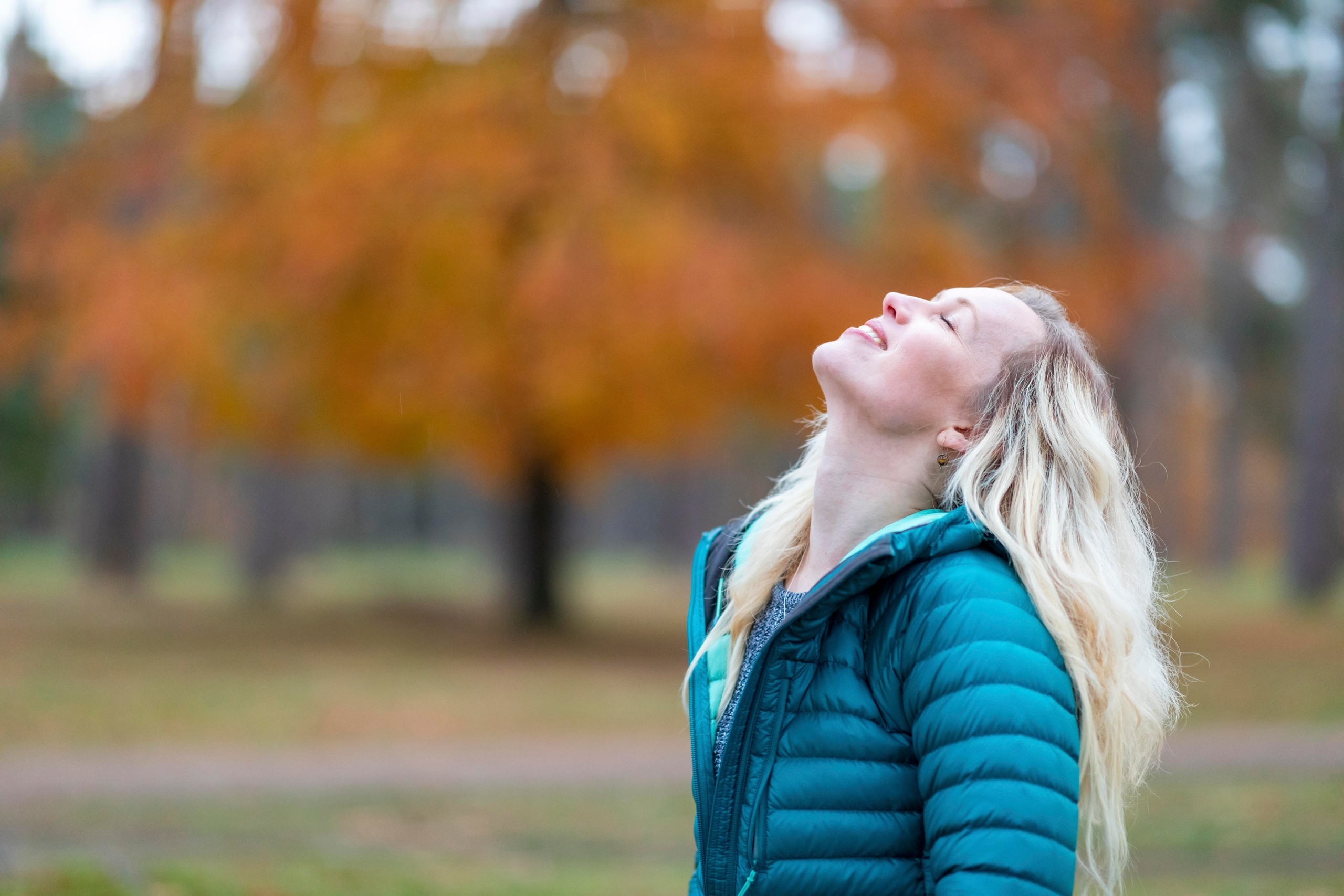 Eine Frau steht im Park und lächelt mit geschlossenen Augen. Selbstliebe bedeutet, mit sich selbst befreundet zu sein, zu seinen Bedürfnissen und Wünschen zu stehen und die eigenen Schwächen zu akzeptieren. Wie du lernst, dich selbst zu lieben. | Bild: picture alliance / Westend61 | William Perugini