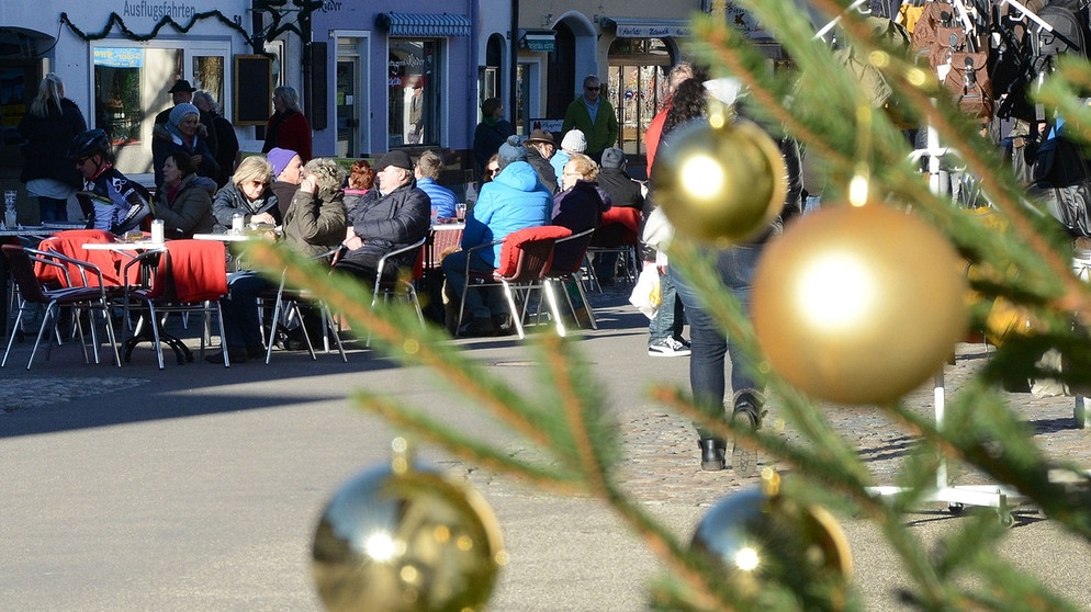 Bei milden Temperaturen genießen Menschen vor einem Lokal in Mittenwald am 20. Dezember 2015, dem Vierten Advent, den Sonnenschein. Der Dezember 2015 war der wärmste je in Bayern gemessene Dezember. Mancherorts waren die Temperaturen um mehr als fünf Grad über dem langjährigen Mittel. | Bild: picture-alliance/dpa