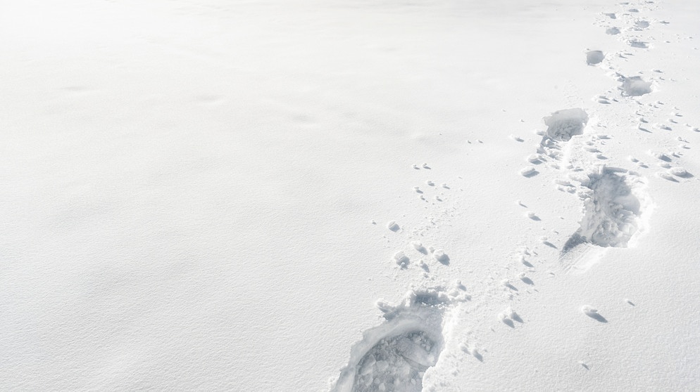 Fußstapfen im Schnee. Wir erklären euch, wann Eiskristalle und Eisblumen entstehen und warum Eiskristalle sechseckig sind. Außerdem erfahrt ihr, was der Unterschied zwischen Eiskristallen und einer Schneeflocke ist und wie viele Eiskristalle in einer Schneeflocke sind. | Bild: picture-alliance/dpa