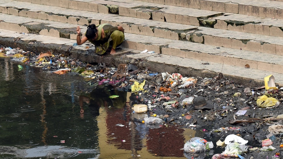 Eine Frau beim Gebet am Ganges in Kalighat, einem Stadtteil von Kolkata. Im Wasser schwimmt Müll. | Bild: picture alliance / Pacific Press | Sudipta Das