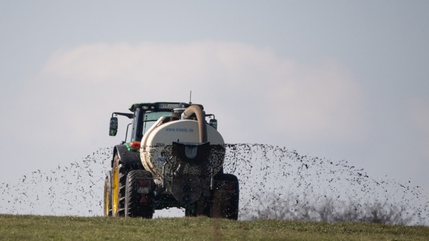 Traktor verspritzt Gülle auf einem Feld | Bild: picture-alliance/dpa