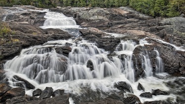 Ein Wasserfall im Sand River in Kanada. Flüsse rings um den Globus transportieren etwa 20 Milliarden Tonnen Sand pro Jahr in die Ozeane. Der Sand entsteht über Jahrtausende durch Erosion von Gestein in den Bergen. | Bild: picture-alliance/dpa