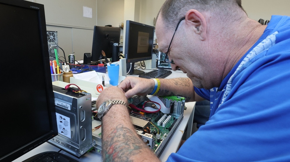 In einer Werkstatt repariert ein Mann einen Computer. | Bild: dpa-Bildfunk/Bodo Schackow