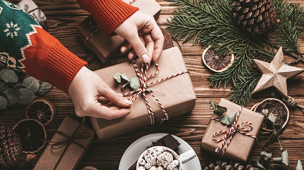 Eine Frau packt Geschenke ein. Weihnachtsbaum, Plätzchen, Braten und Geschenkpapier sind oft wenig umweltfreundlich. Wie ihr mit einfachen Tipps und Tricks ressourcenschonende und trotzdem schöne Weihnachten feiern könnt. | Bild: picture-alliance/dpa
