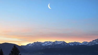 abnehmende Mondsichel morgens kurz vor Neumond über dem Ammergebirge (und dem Forggensee) im November 2015 | Bild: imago/blickwinkel