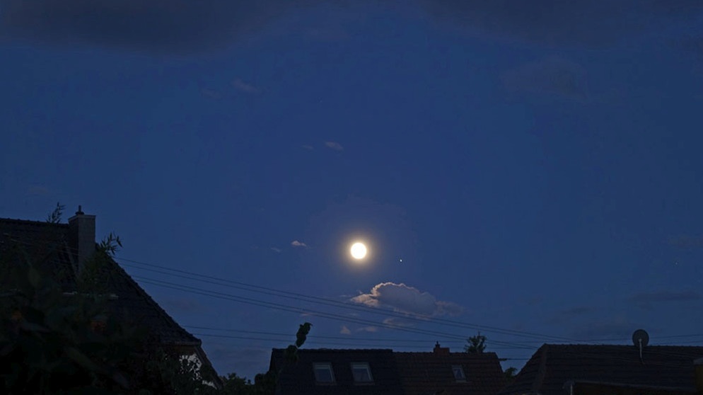 Planet Jupiter am 16. Juni 2019 neben dem Vollmond. Jupiter, der größte Planet im Sonnensystem, ist so hell, dass ihm selbst die helle Mondscheibe, nur einen Fingerbreit entfernt, wenig ausmacht. | Bild: Heinrich Sommerkorn