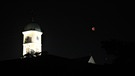 Mondfinsternis mit rotem Blutmond fotografiert neben einem Kirchturm (Stadtamhof) in Regensburg.  | Bild: Christoph Rippler