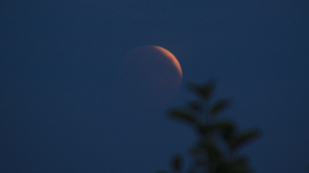 Der erste Rand des Blutmondes taucht hinter den Dunstschichten während der totalen Mondfinsternis am 27. Juli 2018 über Barbing Illkofen auf. | Bild: Katharina Beiler