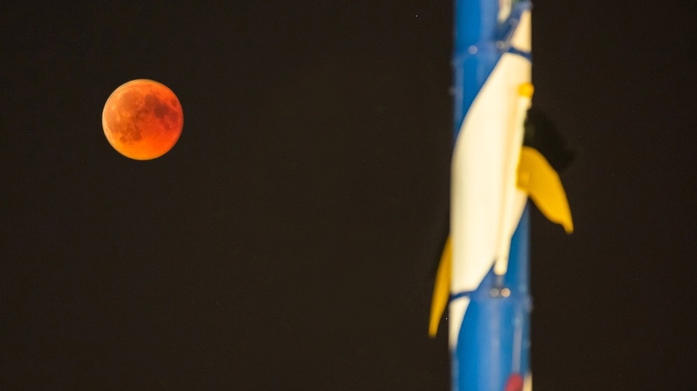 Der Blutmond während der totalen Mondfinsternis am 27. Juli 2018 neben dem Maibaum am Viktualienmarkt in München, aufgenommen von Folke Ashberg | Bild: Folke Ashberg